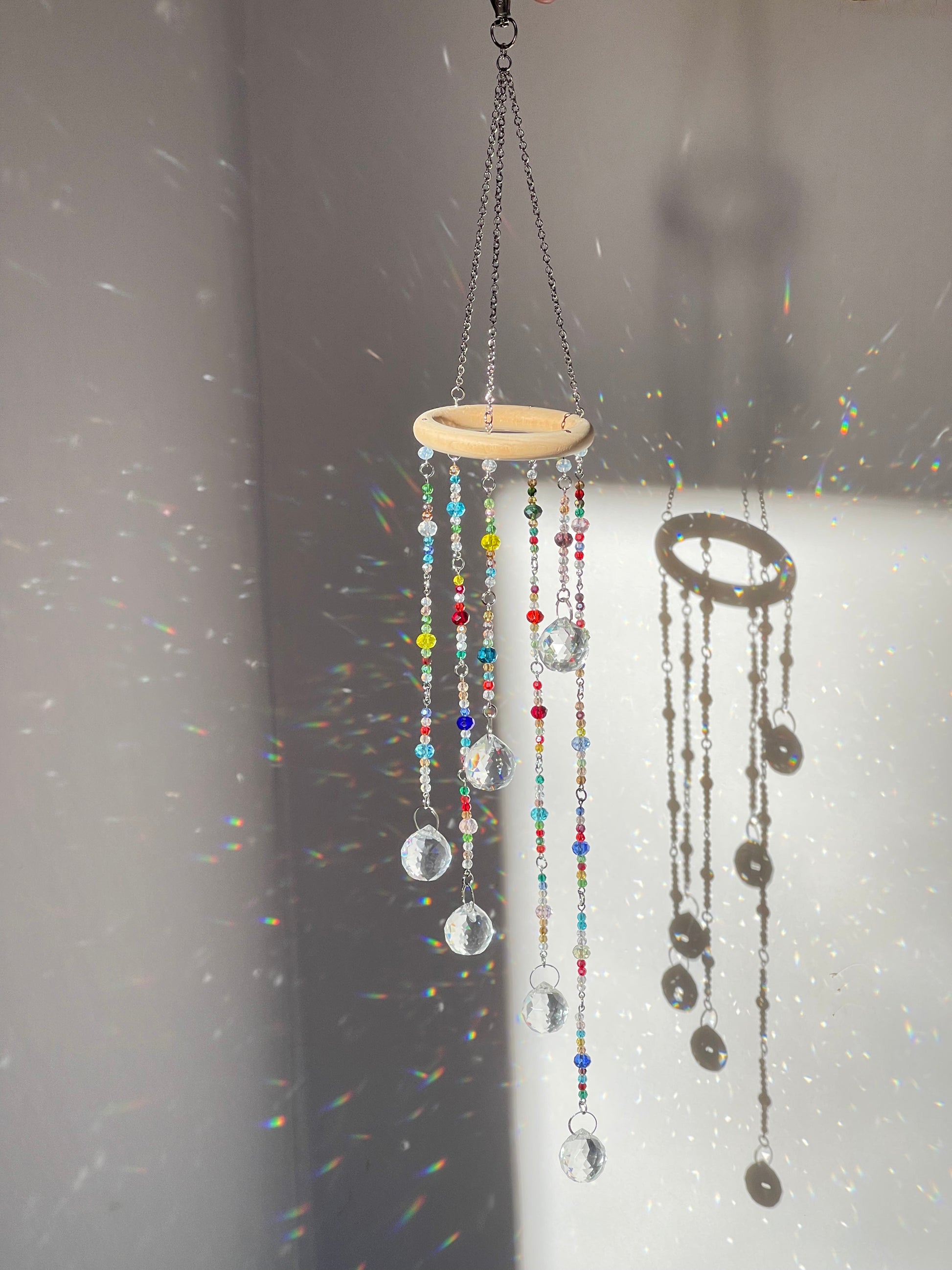 Handmade boho crystal mobile with clear 1 inch rainbow-maker prisms catching sunlight